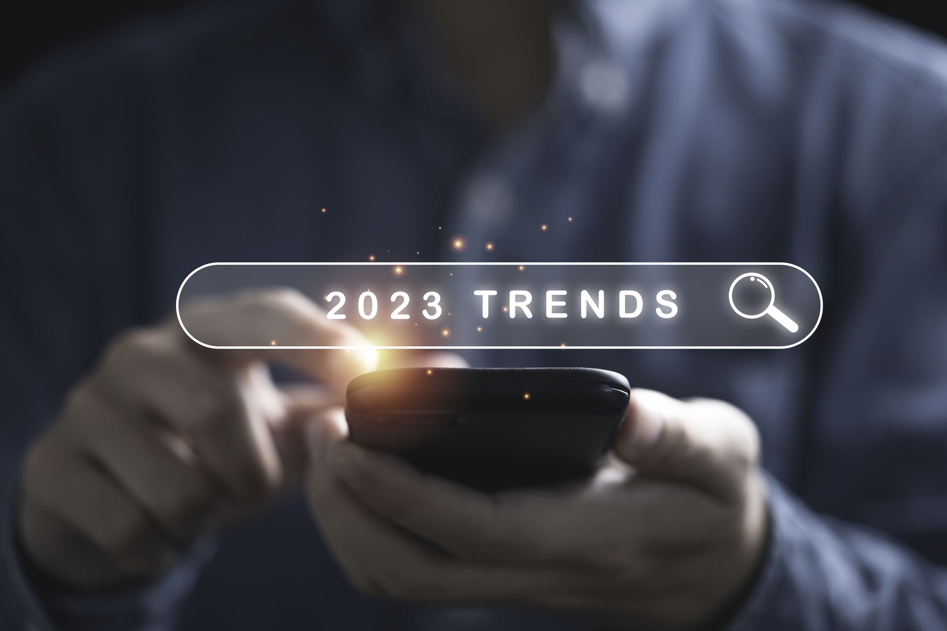 hands holding cell phone with the words trends 2023 floating above it